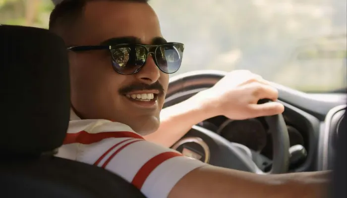 Mann am Steuer schaut zurück und lächelt in Kamera